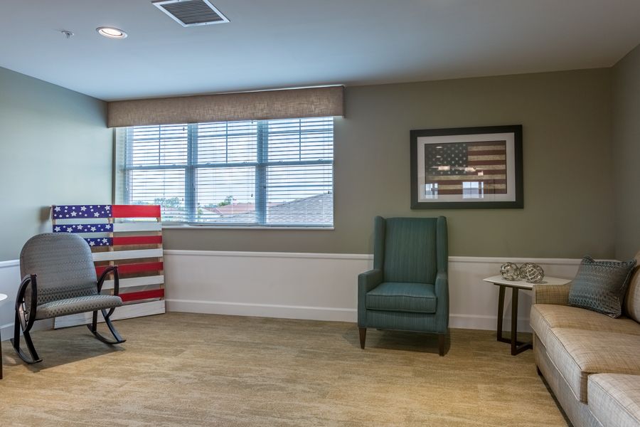 A cozy living room with a green armchair, a side table, and a framed picture on the wall.