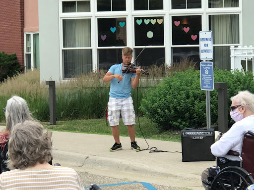 A young musician performing on the street with a violin, entertaining an outdoor audience.