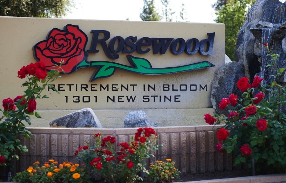 Entrance sign for Rosewood Retirement Home surrounded by vibrant flowers.