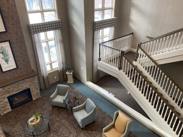 A spacious lobby area featuring a modern staircase, comfortable seating, and large windows.