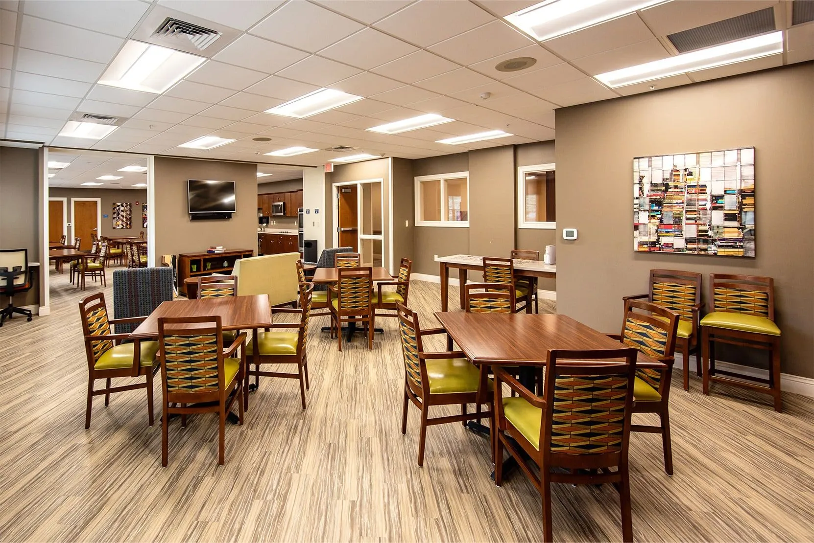A well-lit dining area with multiple tables and chairs, featuring wooden flooring.