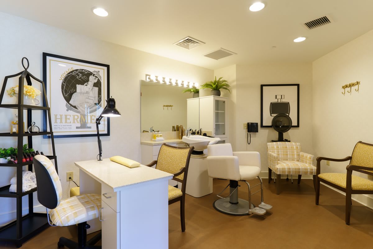 A modern and stylish hair salon interior featuring seating, mirrors, and artwork on the walls.