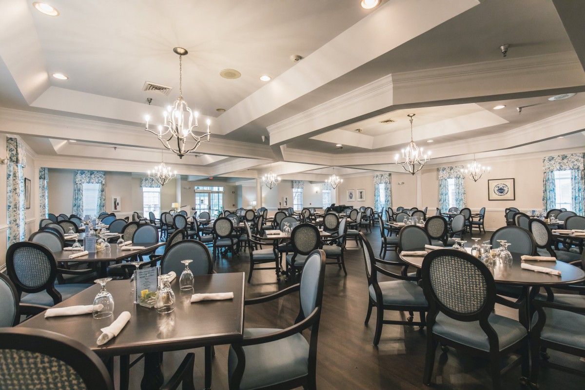 An elegant restaurant dining room with chandeliers and neatly arranged tables and chairs.