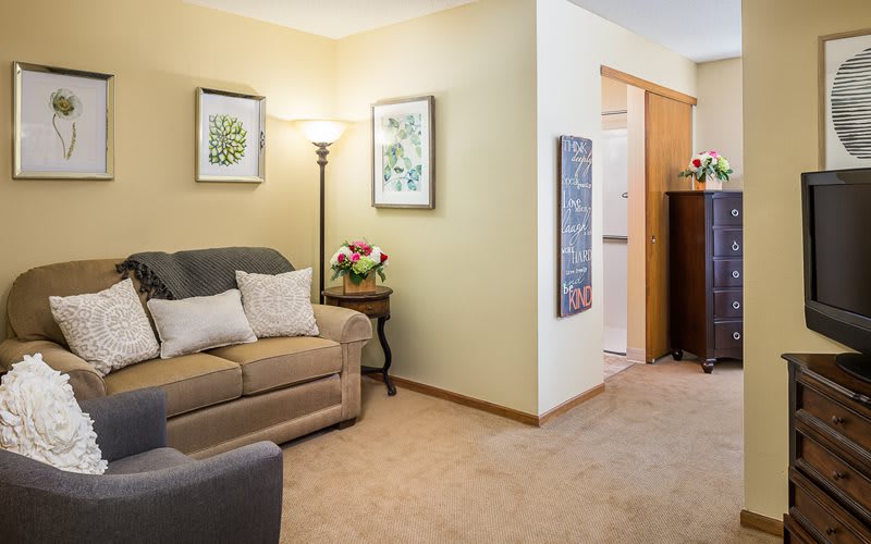 A cozy living room with a sofa, floor lamp, and decorative artwork on the walls.