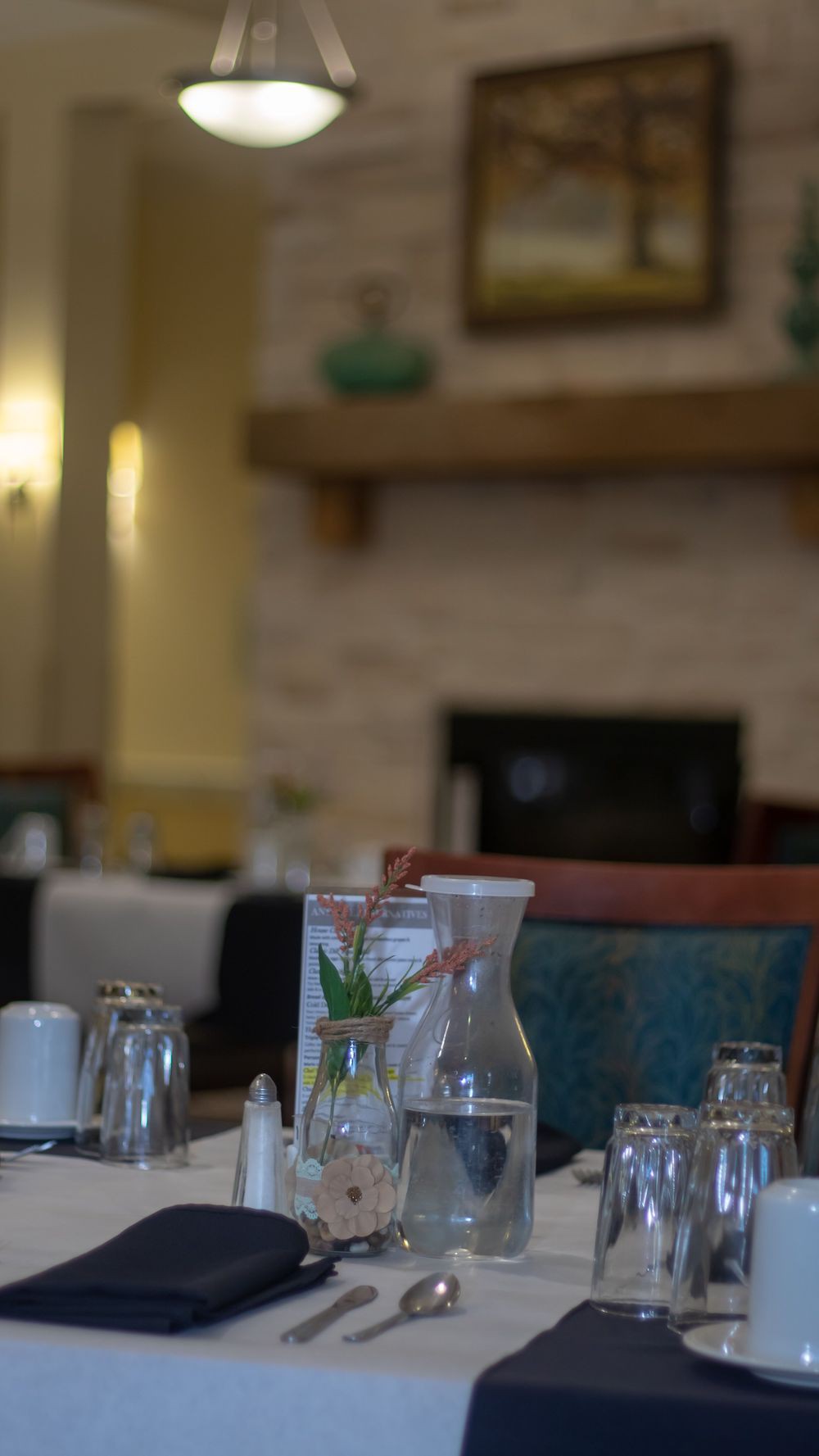 A cozy restaurant interior with a neatly set dining table near a fireplace.