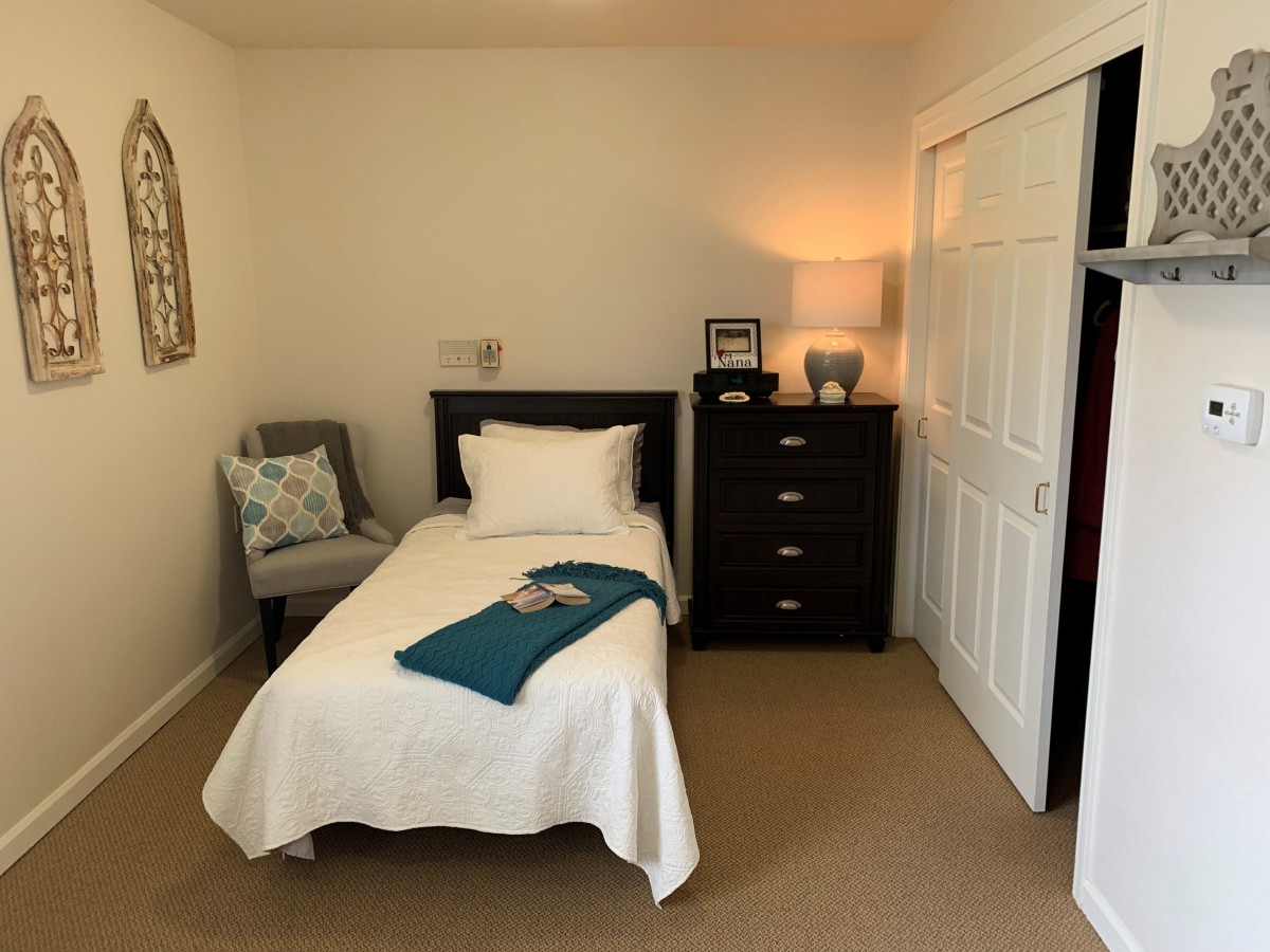 Cozy bedroom with a single bed, dresser, and soft lighting.
