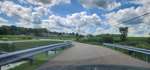 A winding road through a scenic countryside landscape under a partly cloudy sky.