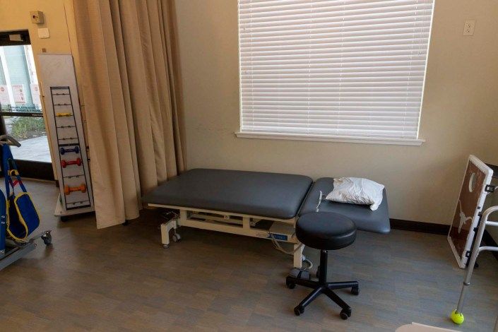 A medical examination room with a treatment table and stool.