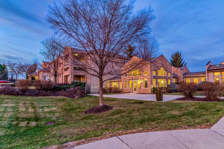 A beautifully lit residential house in the evening with a well-maintained yard.