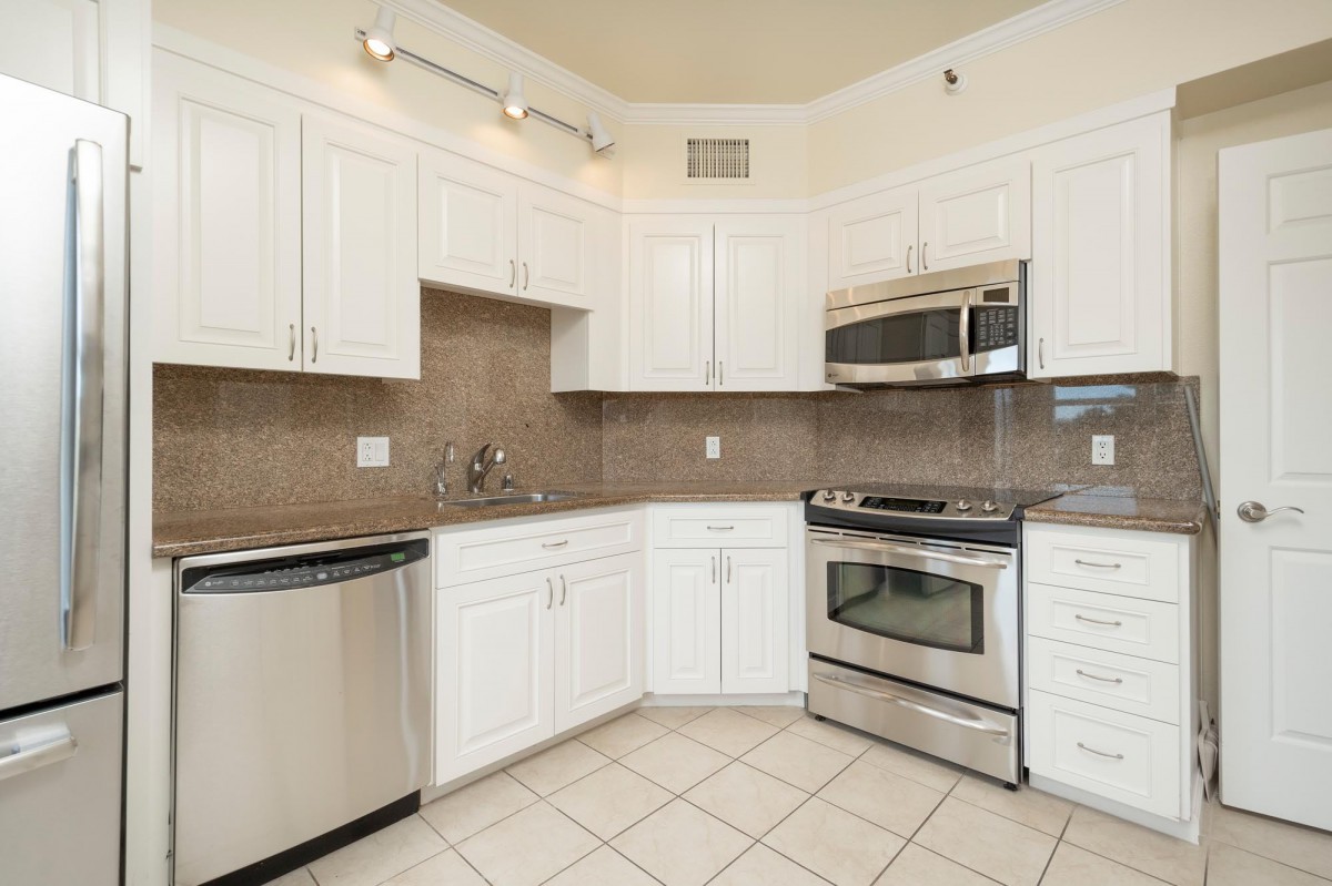 A modern kitchen featuring white cabinetry and stainless steel appliances.