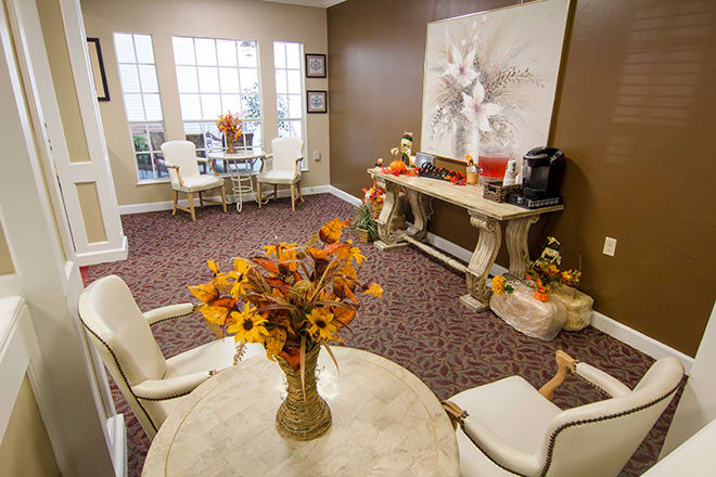 A cozy living room with elegant furnishings, floral decorations, and large windows.