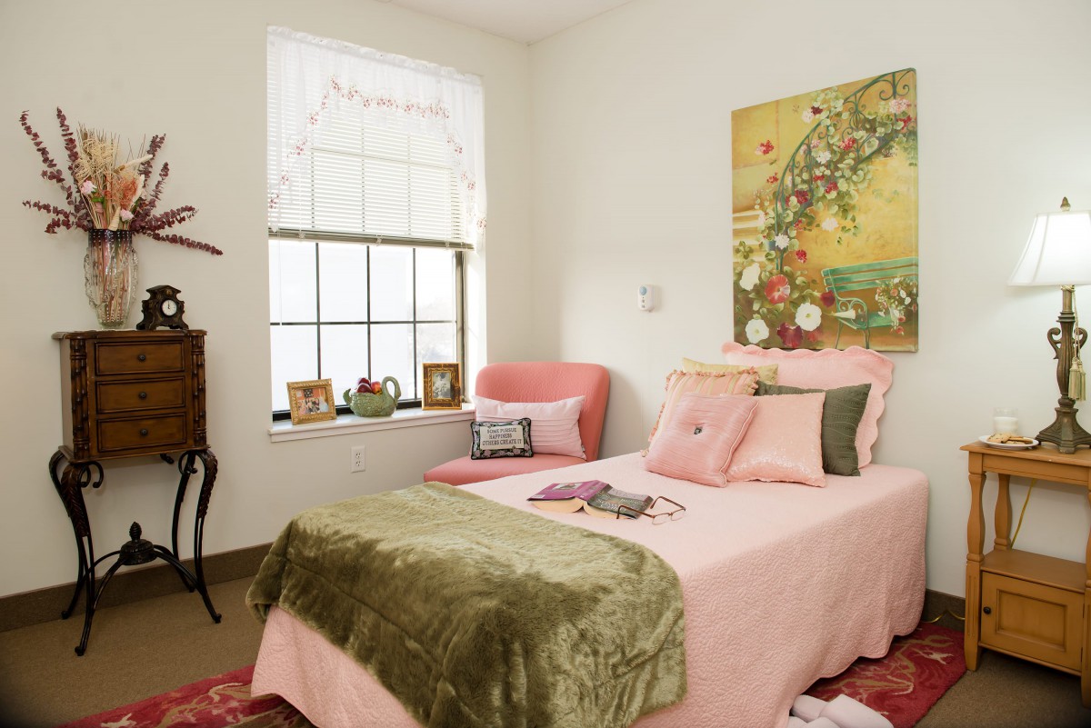 A cozy bedroom featuring pink bedding, elegant decor, and a large artwork on the wall.