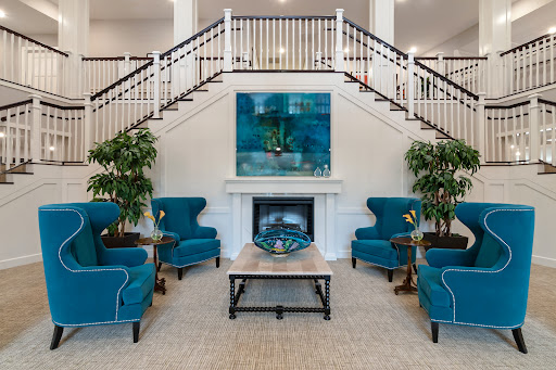 A stylish lobby featuring cozy teal armchairs, a modern fireplace, and an elegant staircase.