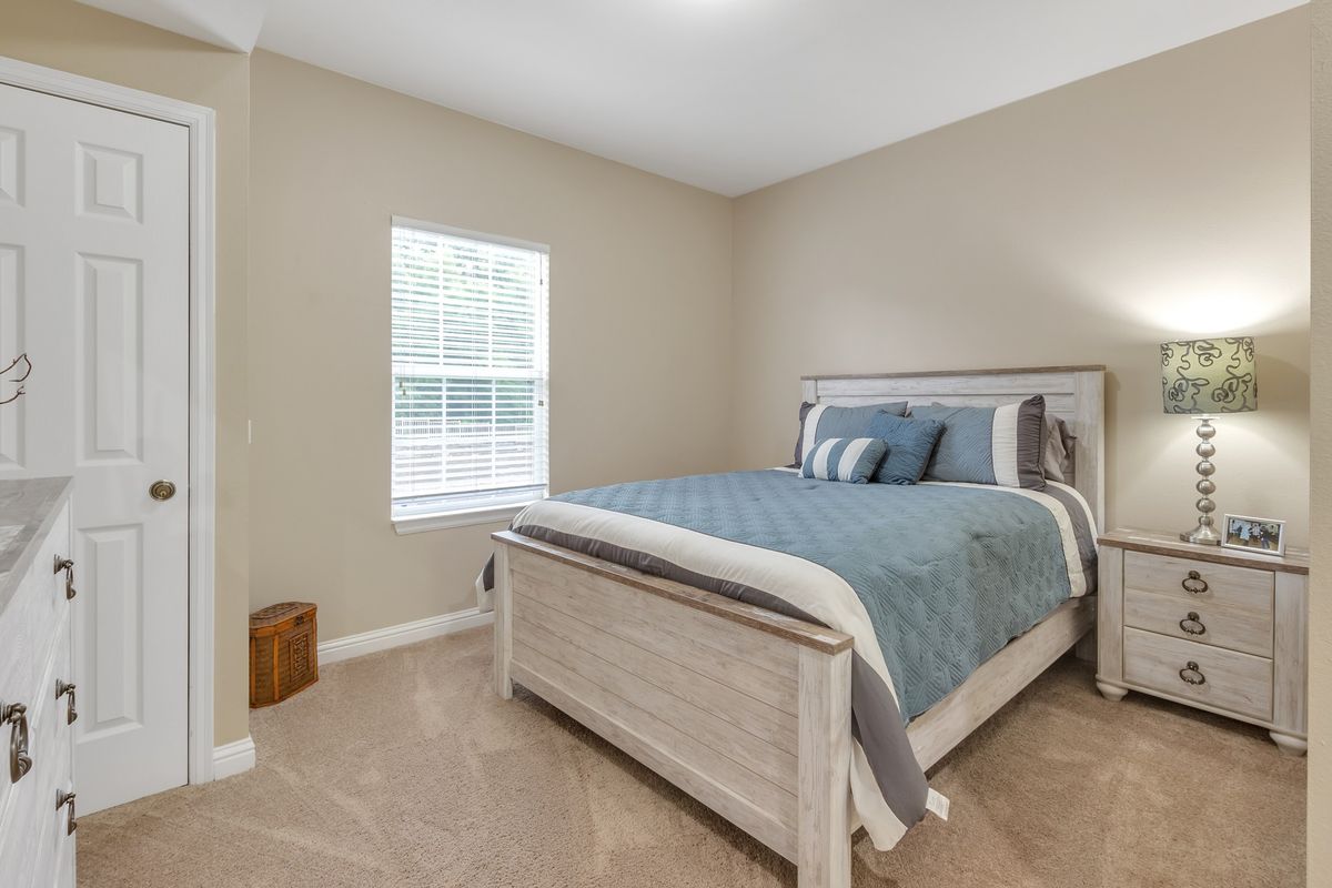A cozy bedroom with a neatly made bed and natural light from the window.