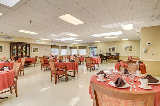 A spacious dining area featuring round tables with red tablecloths and decorative place settings.