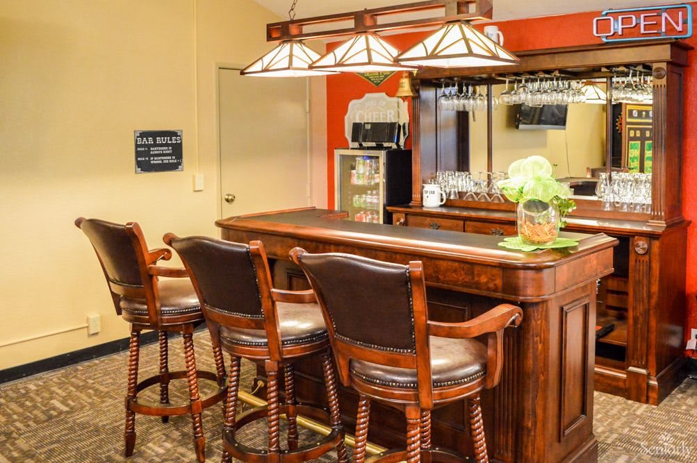 A cozy indoor bar setup with a wooden counter and high chairs.