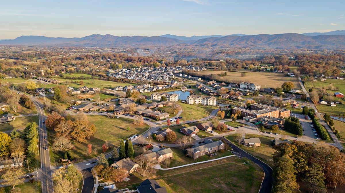 Aerial view of a suburban neighborhood surrounded by countryside and mountains in the distance.