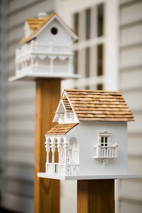 A detailed wooden birdhouse with intricate design and shingled roof.