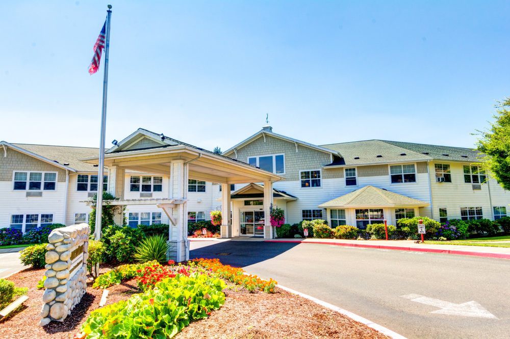 A bright day at a large building with landscaped gardens and an American flag.
