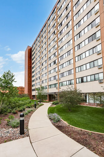 A modern apartment building surrounded by landscaped gardens and pathways.