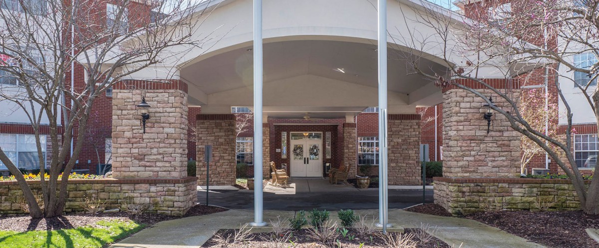 The entrance of a building with brick walls and columns under an awning.