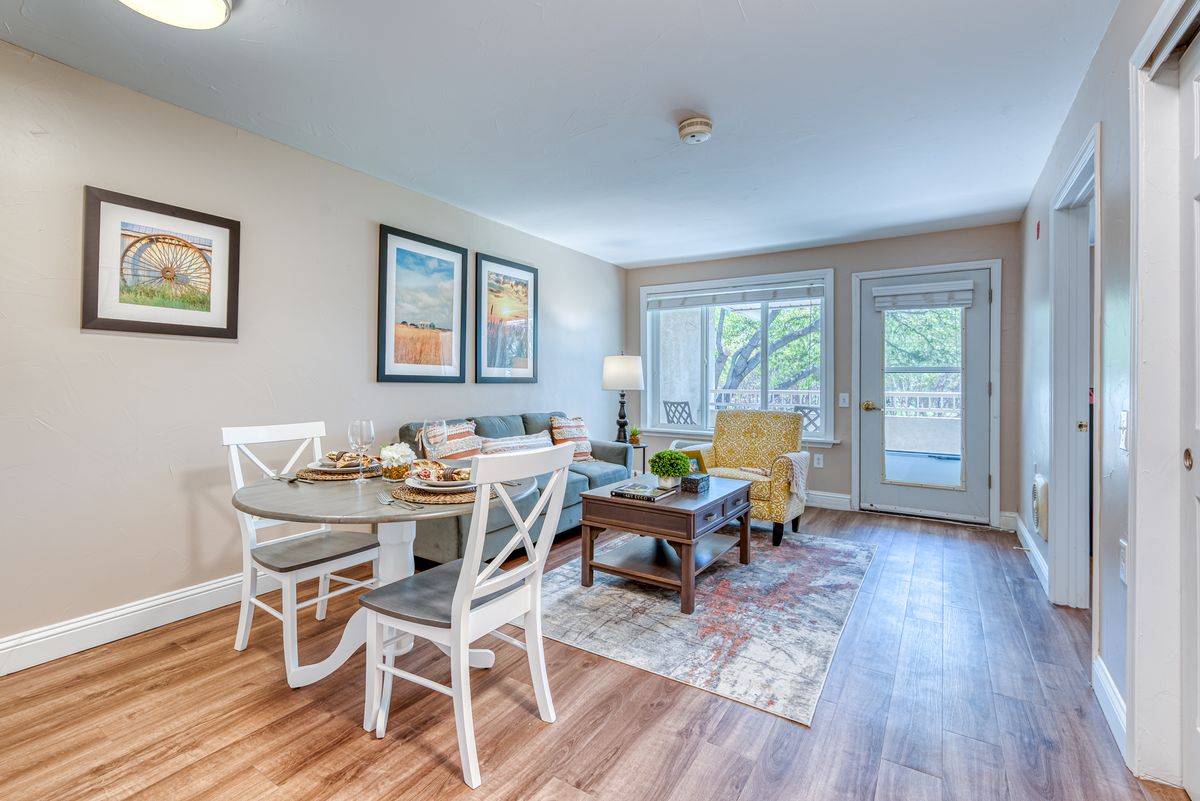 A bright and cozy living room with a dining area featuring wooden flooring, stylish furniture, and art on the walls.