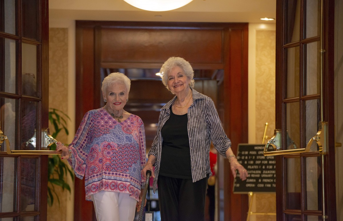 Two elderly women smiling together indoors.
