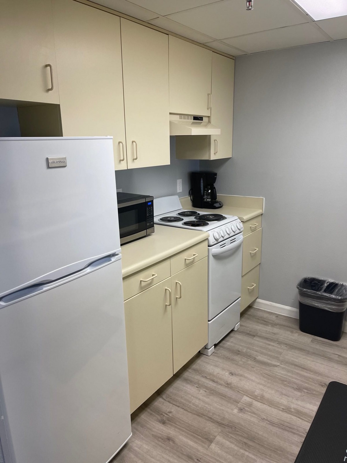 A compact kitchen with essential appliances including a refrigerator, microwave, stove, and coffee maker.
