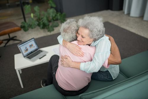 A touching moment between two elderly friends sharing a warm embrace.
