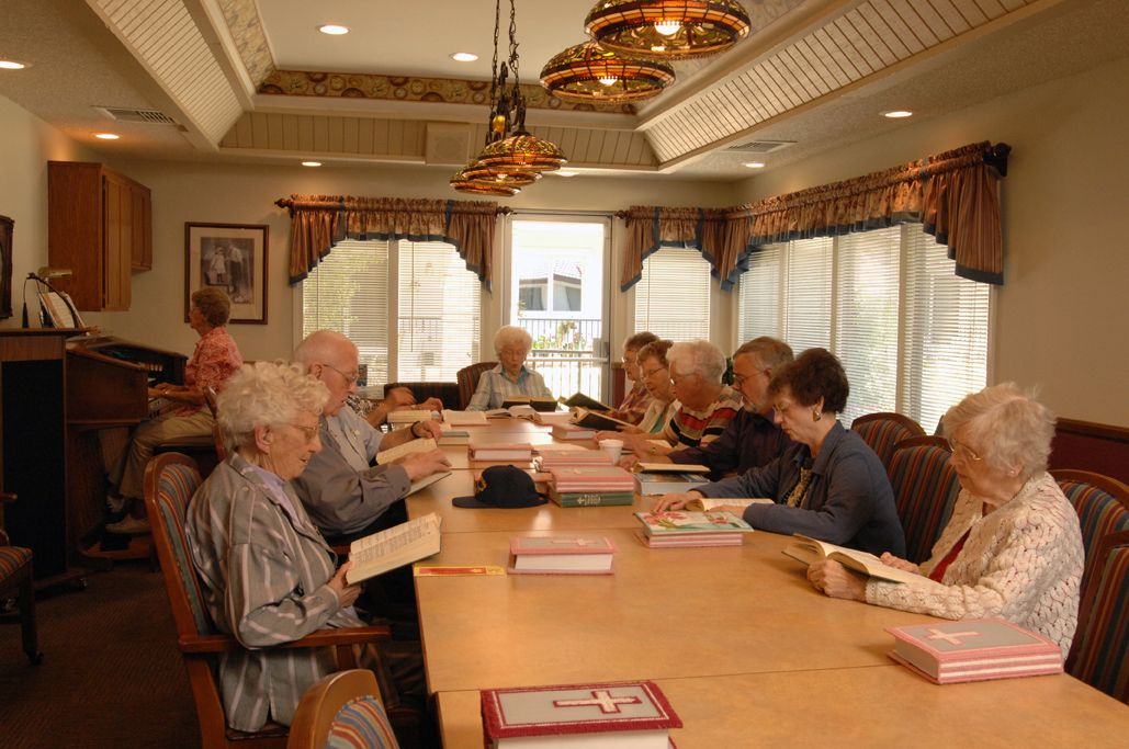 A group of senior citizens engaged in a book club discussion around a large table.