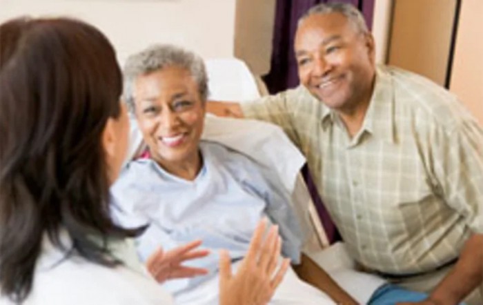 A patient receives support and care from a doctor and family member in a hospital setting.