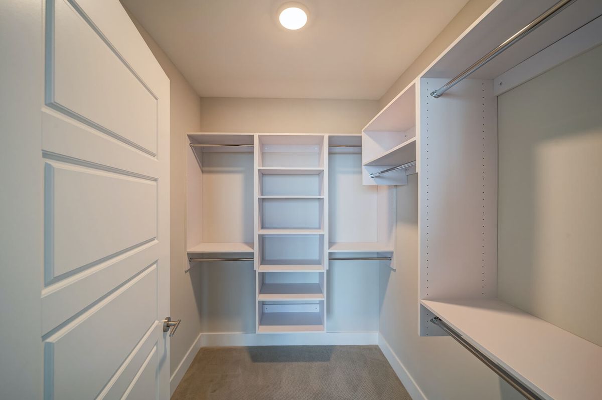 An empty walk-in closet with built-in shelves and hanging rods for organization.