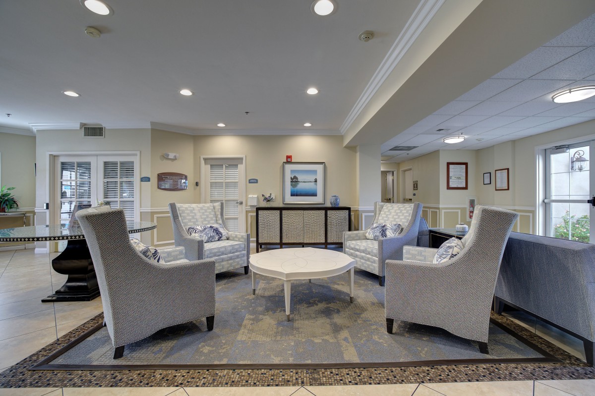 A modern living room with neutral tones, featuring comfortable lounge chairs and a central coffee table.