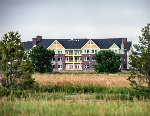 A colorful residential building surrounded by trees and grasslands.