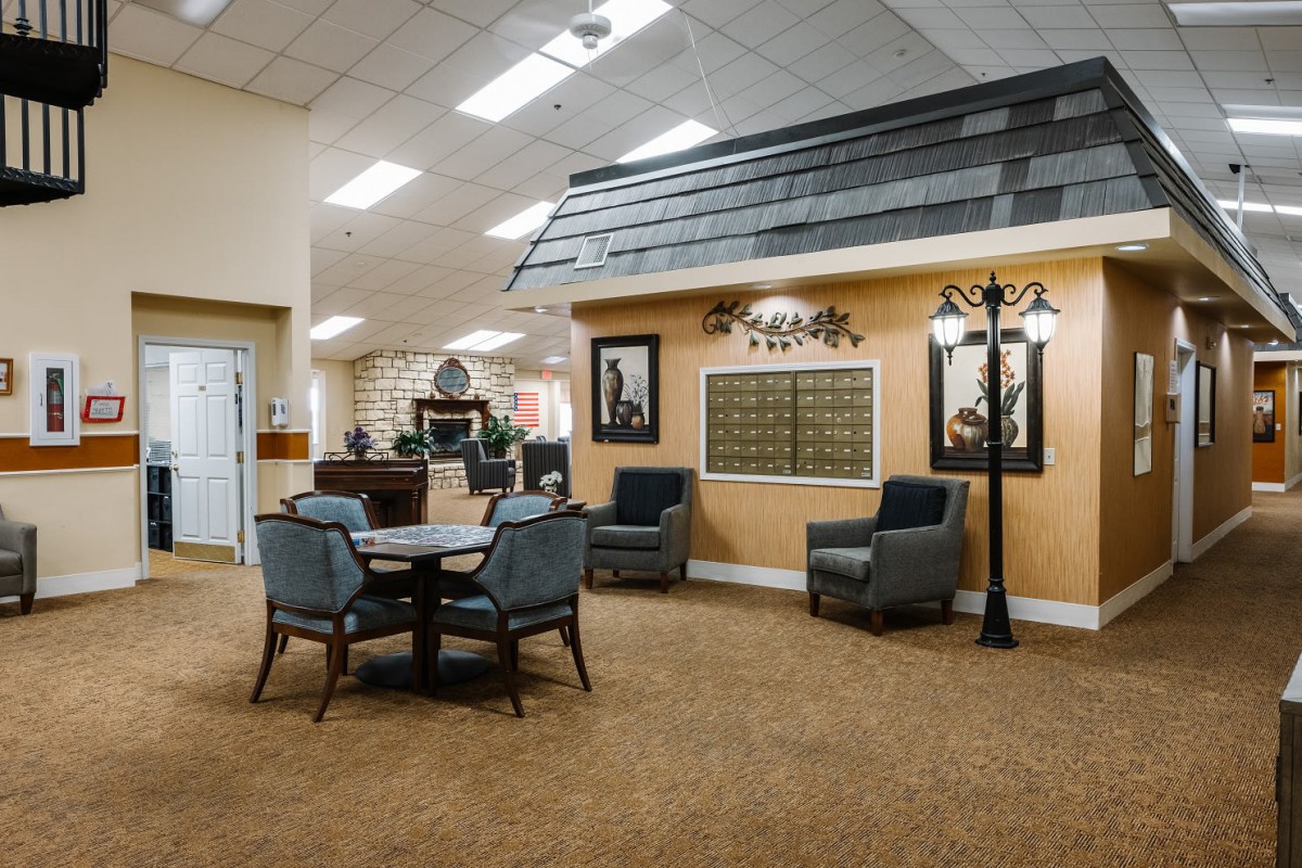 A cozy interior space featuring a seating area with chairs and a table, decorated with wall art and illuminated by indoor lighting.