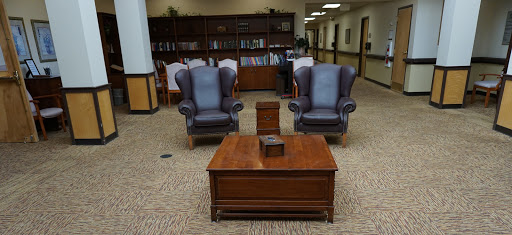 A cozy seating arrangement featuring two armchairs and a wooden coffee table in a library setting.