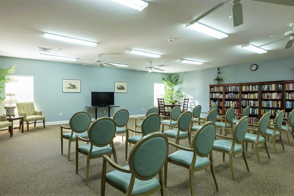 A well-lit meeting room with arranged chairs, a television, and a bookshelf.