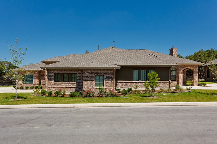 A single-story brick house in a suburban neighborhood with landscaped surroundings.