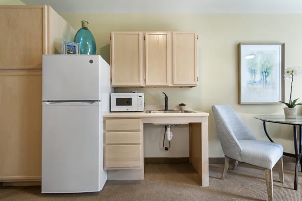 A compact kitchenette featuring a refrigerator, microwave, sink, and cabinets.