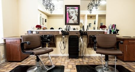 A chic hair salon interior with styling chairs and mirrors, adorned with vintage artwork.