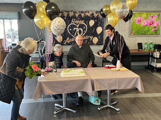 A joyful celebration marking a special anniversary with loved ones, complete with balloons, a cake, and flowers.