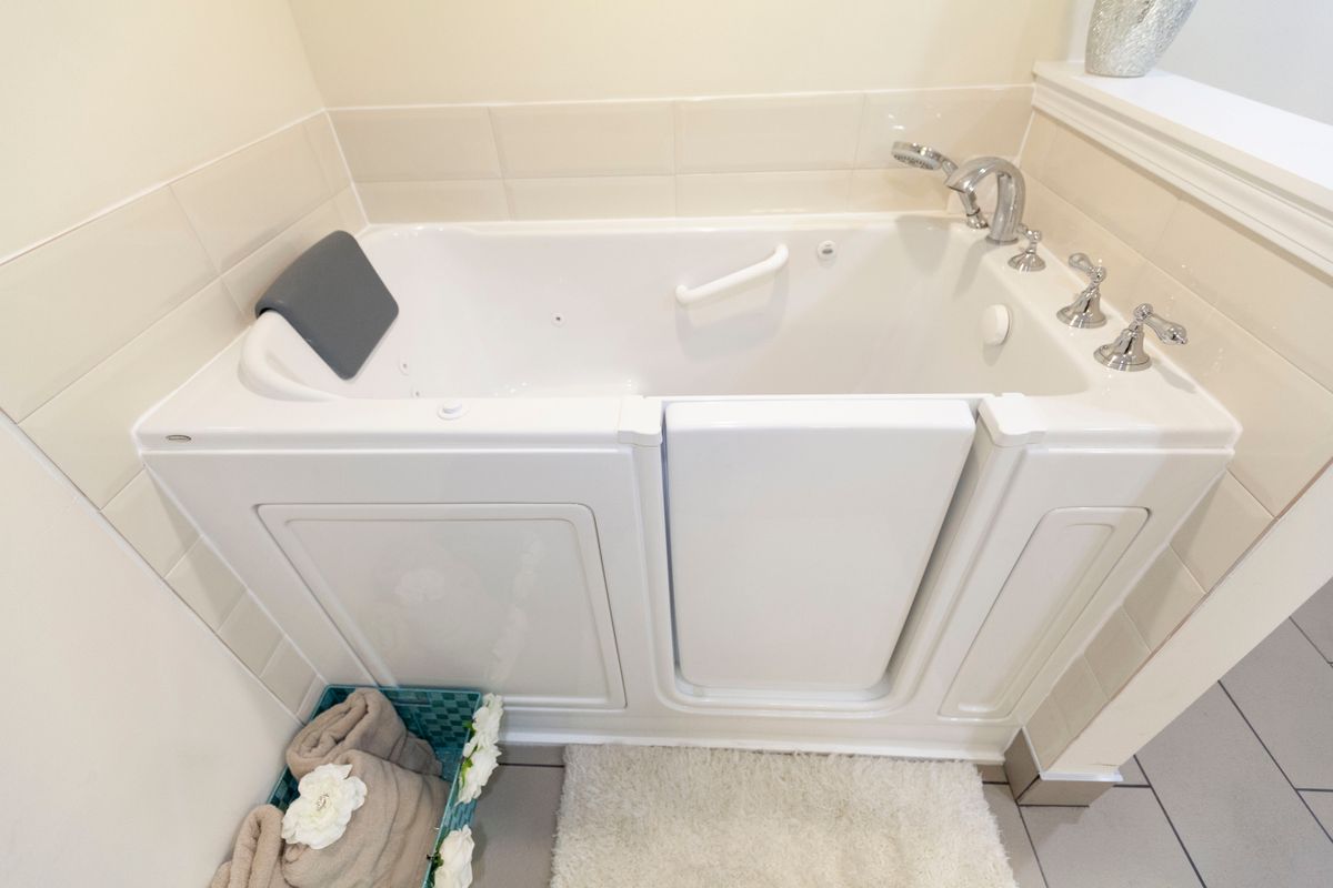 A bathroom featuring an accessible walk-in bathtub with towels neatly arranged.
