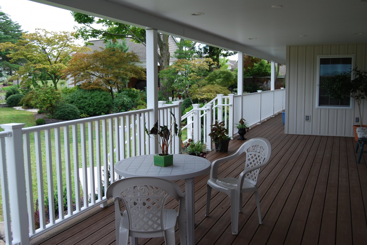 A peaceful porch with a table and chairs overlooking a garden.