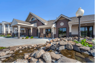 A beautiful residential house with a landscaped front yard featuring rocks and a small pond.