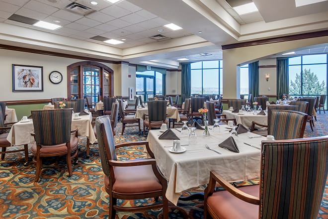 An elegantly set restaurant dining room with multiple tables ready for guests.