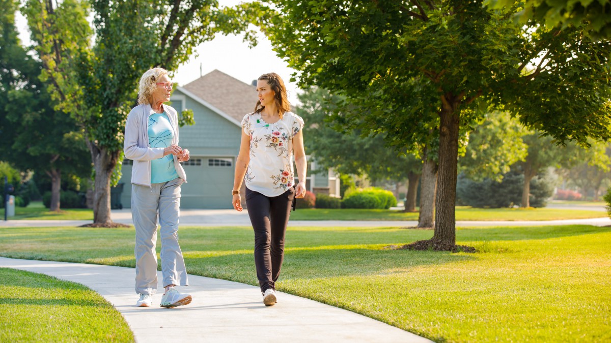 Two people engaged in conversation while walking through a neighborhood.