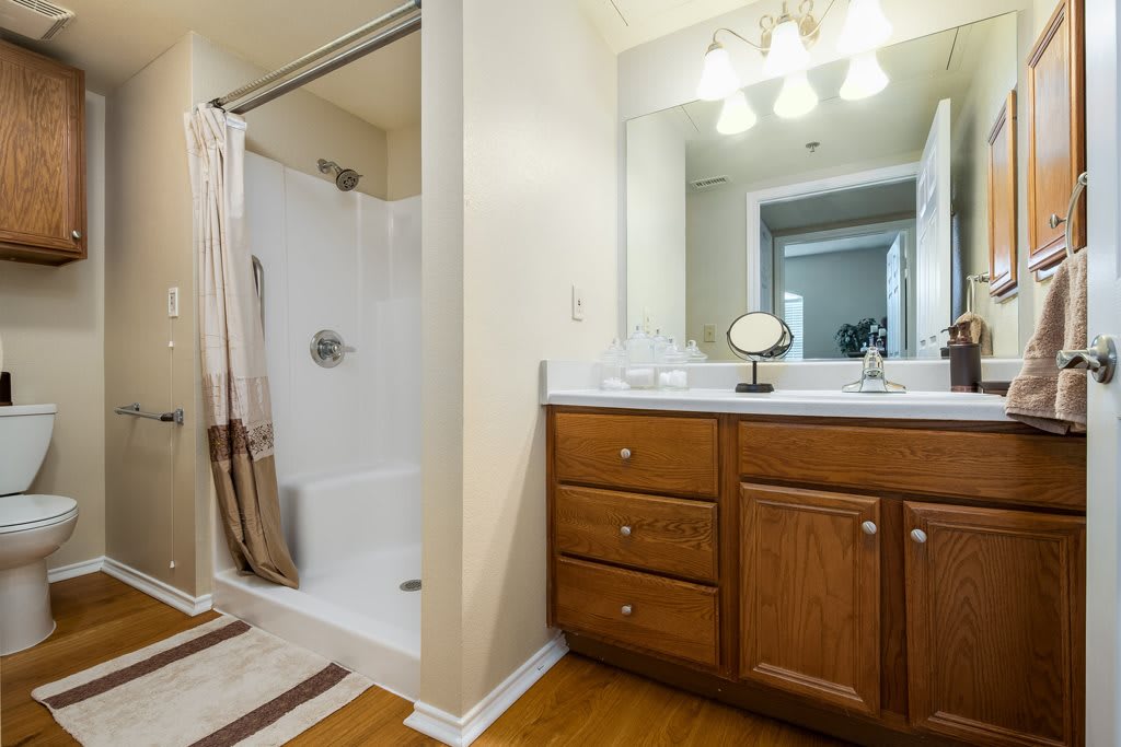 A cozy bathroom with a shower, wooden vanity, and large mirror.