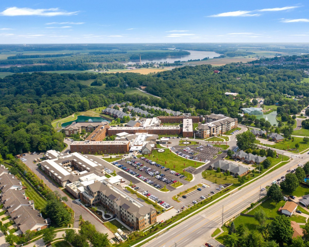 An aerial view of a large complex with buildings, parking lots, and surrounding greenery.
