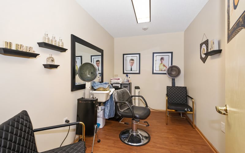 A cozy hair salon with styling chairs and framed pictures on the wall.
