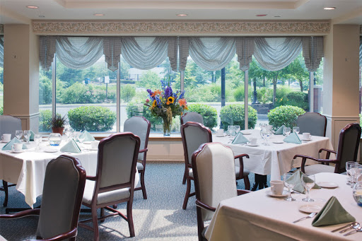 A beautifully arranged dining room with elegant decor, featuring flowers and a scenic view.